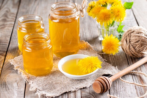 Photo miel de pissenlit dans un pot et fleurs fraîches sur une table en bois