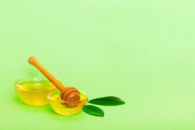 Miel en pot avec feuilles et louche de miel sur la vue de dessus de fond coloré avec copie de texte