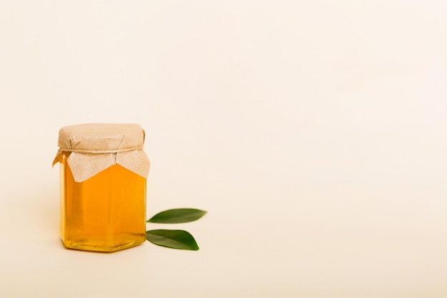 Miel en pot avec feuilles et louche de miel sur la vue de dessus de fond coloré avec copie de texte