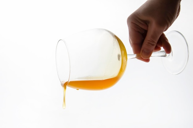 Le miel qui coule d'un verre à vin sur un fond blanc. aliments bio vitaminés
