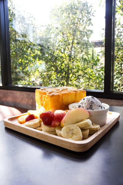 Miel toast avec des fruits frais sur une plaque en bois.