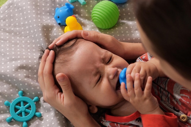 Mignon adorable bébé nouveau-né jouant avec un jouet hochet coloré bébé avec un anneau de dentition de six mois joli portrait de bébé sur blanc avec un jouet de dentition