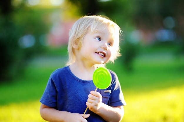 Mignon bambin avec grosse sucette verte. Enfant mangeant des friandises sucrées. Bonbons pour les jeunes enfants. Plaisirs d&#39;été en plein air