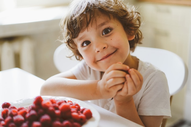 Mignon beau petit garçon mangeant des framboises fraîches. Alimentation saine, enfance et développement.