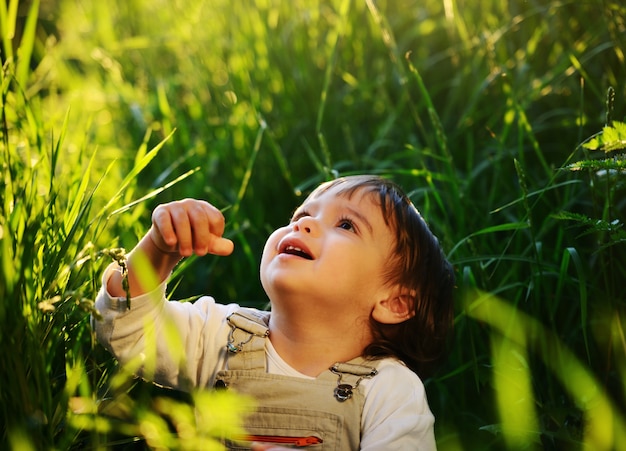 Mignon bébé adorable assis dans la belle herbe verte