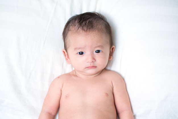 Mignon bébé asiatique allongé sur un oreiller blanc, sur le lit
