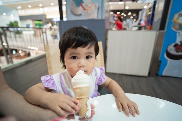 Mignon bébé asiatique mangeant de la crème glacée au restaurant