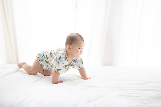 Photo mignon bébé asiatique rampant dans son lit