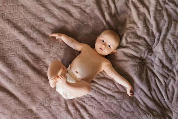 Mignon bébé doux dans une couche allongé sur le lit sur le dos