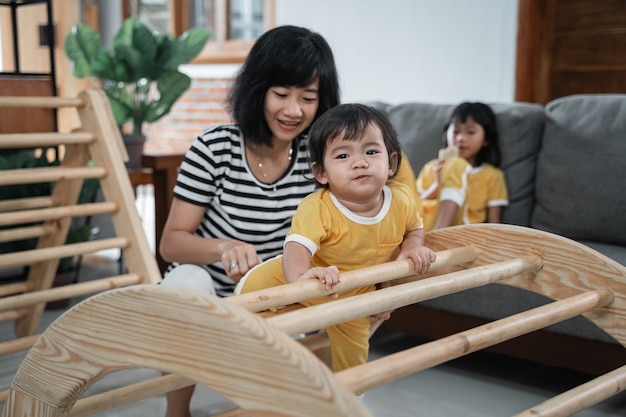 Mignon bébé escalade pikler jouets d'escalade avec sa mère tout en jouant ensemble dans la maison