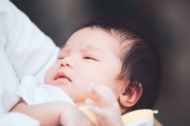 Mignon bébé nouveau-né asiatique dormir sur l&#39;épaule de la mère. Maman câliner bébé avec tendresse.