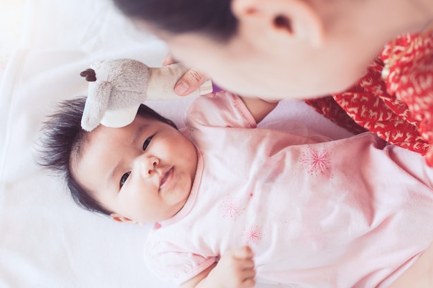 Mignon bébé nouveau-né asiatique jouant avec la mère