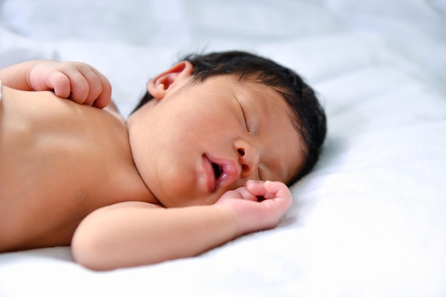 Un mignon bébé qui dort sur le lit.