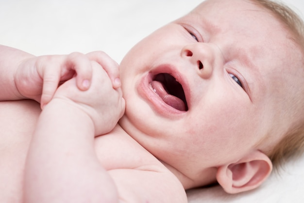 Mignon bébé qui pleure sur un fond clair