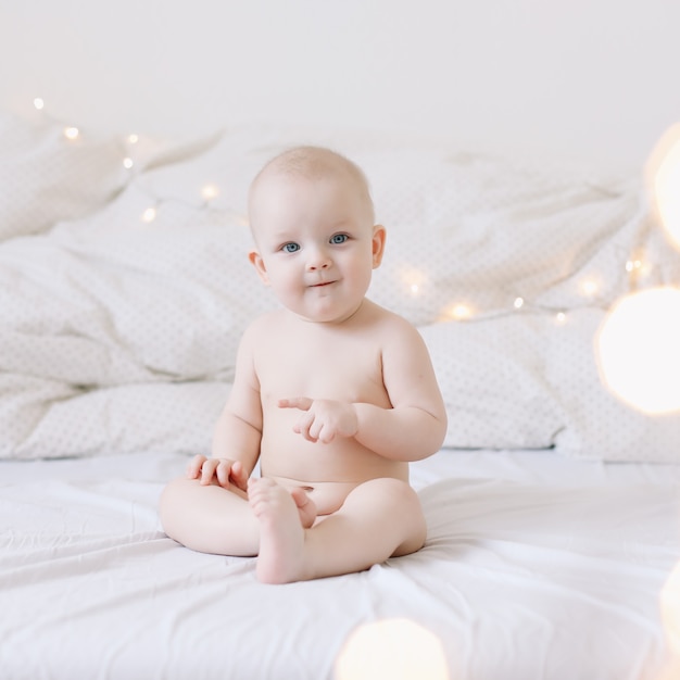 Mignon bébé souriant heureux est assis sur le lit