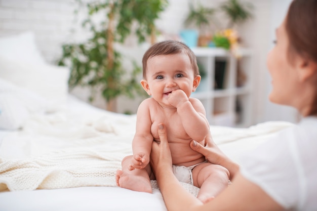 Mignon bébé souriant avec des rayures sur le lit dans la chambre.