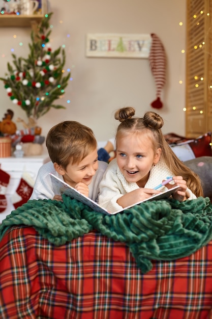 Mignon deux enfants heureux écrivant une lettre au père Noël