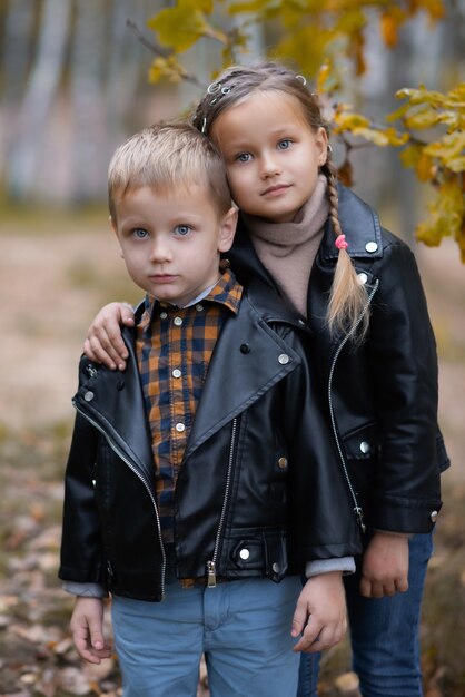 Mignon drôle de petite fille souriante et garçon se serrent dans le parc de l'automne. Joyeux enfants joyeux