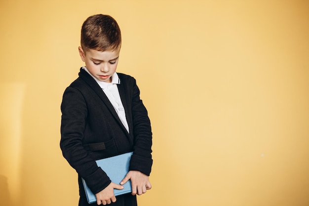 Mignon écolier portant l'uniforme scolaire et tenant des livres