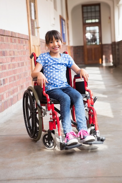 Photo mignon élève handicapé souriant à la caméra dans le hall