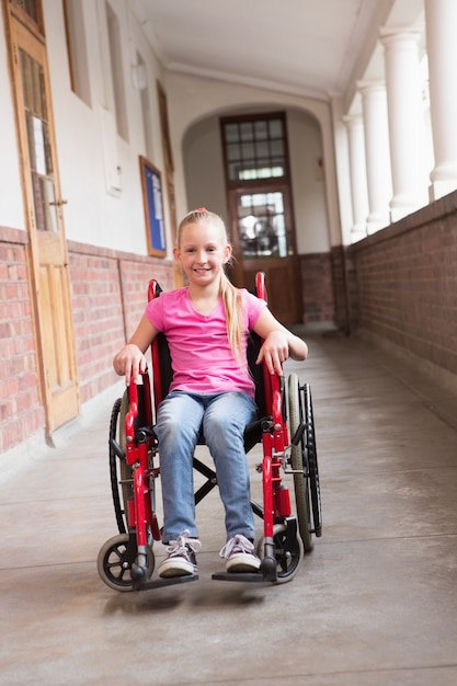 Mignon élève handicapé souriant à la caméra dans le hall