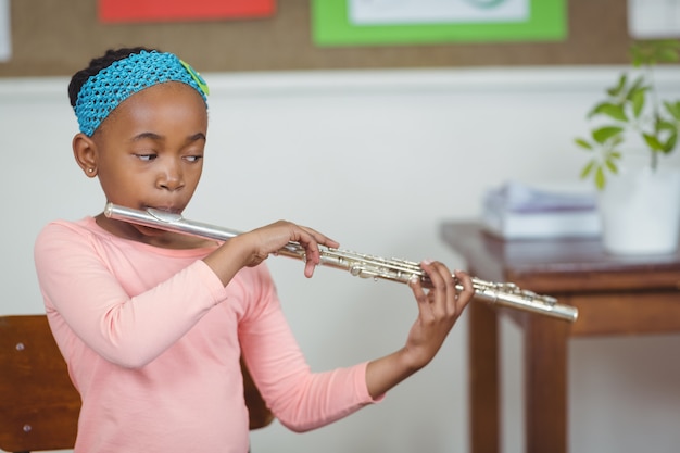 Mignon élève jouant de la flûte dans une salle de classe