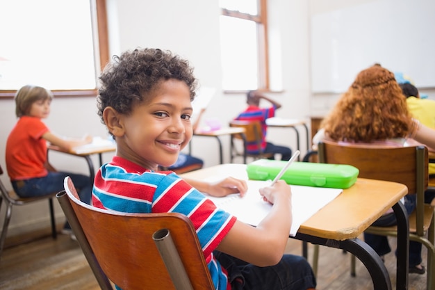 Mignon élève souriant à la caméra dans la salle de classe