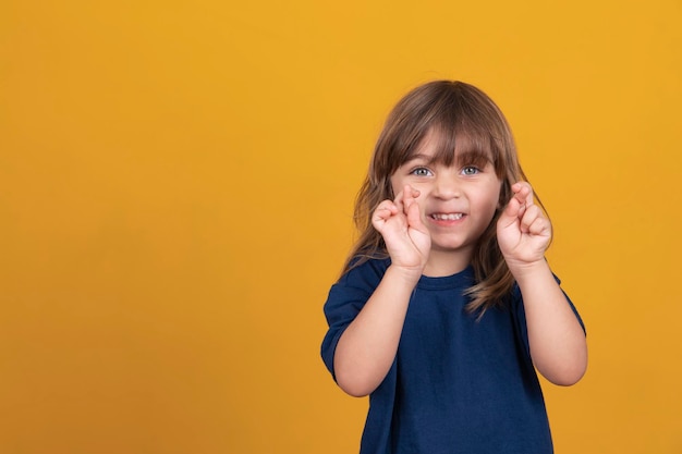 Mignon enfant caucasien fille avec les doigts croisés souhaitant bonne chance