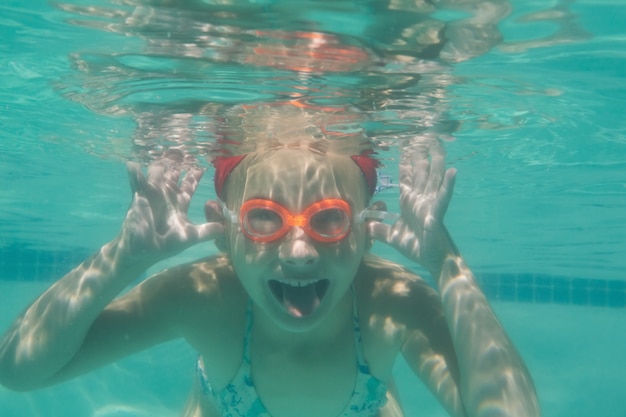 Mignon enfant posant sous l&#39;eau dans la piscine