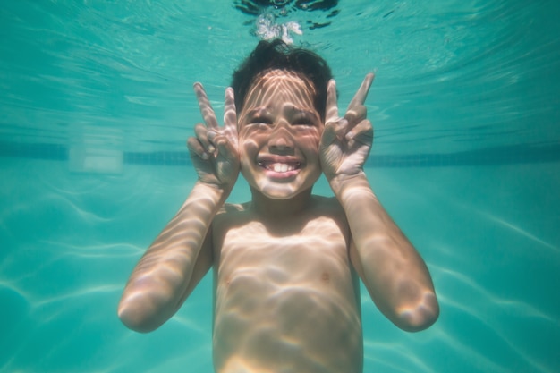 Mignon enfant posant sous l&#39;eau dans la piscine