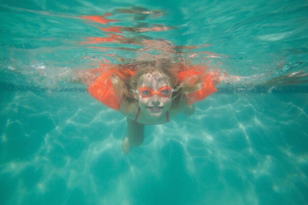 Mignon enfant posant sous l&#39;eau dans la piscine