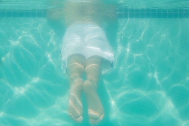 Mignon enfant posant sous l&#39;eau dans la piscine