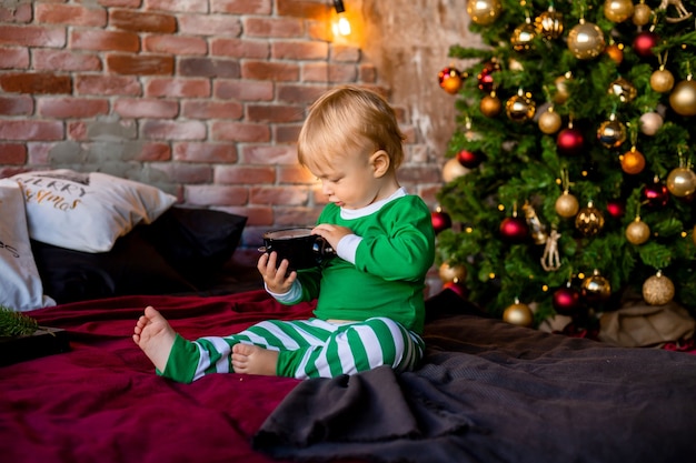 Mignon enfant en pyjama se trouve près de l'arbre de Noël