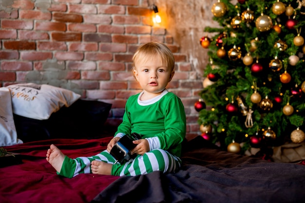 Mignon enfant en pyjama se trouve près de l'arbre de Noël