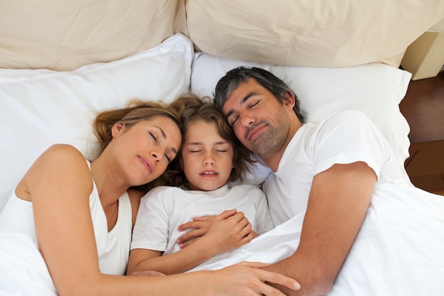 Mignon enfant et ses parents qui dorment ensemble