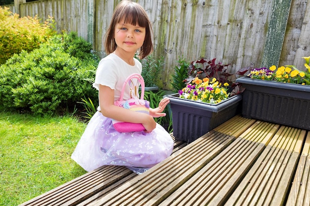 Un mignon enfant souriant joue dans l'arrière-cour avec un petit sac rose Journée ensoleillée Beau temps