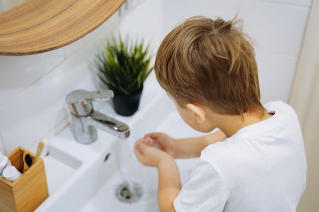 mignon garçon de 6 ans se lavant le visage au-dessus du lavabo dans la salle de bain Image avec mise au point sélective