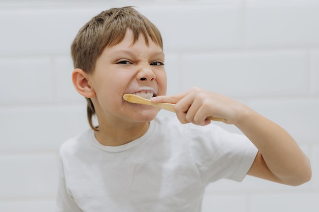 Mignon garçon de 8 ans se brosser les dents avec une brosse à dents en bambou dans la salle de bain Image avec mise au point sélective