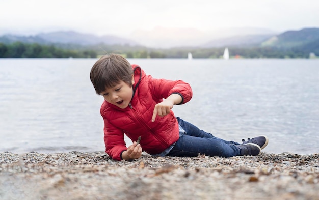 Photo un mignon garçon assis au bord du lac