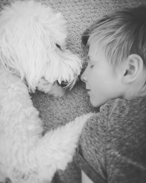 Photo un mignon garçon avec un chien qui dort à la maison.