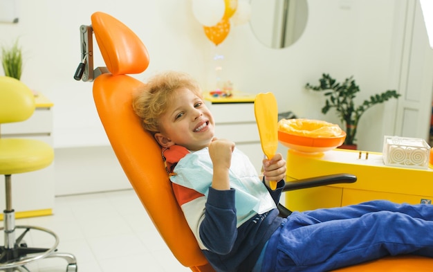 Un mignon garçon est assis dans un fauteuil dentaire dans une clinique moderne Un charmant bébé se penche sur un stamological