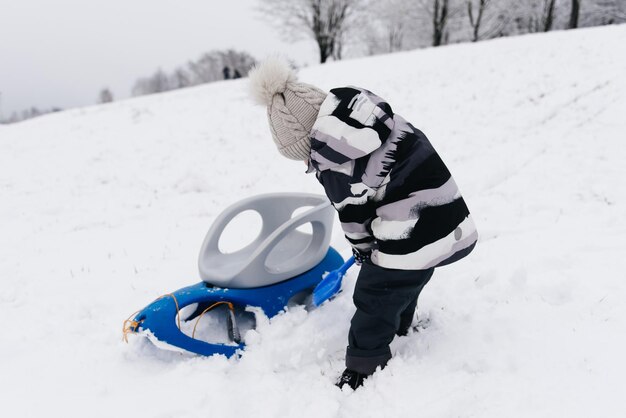 Mignon garçon mignon dans un traîneau dans la famille d'hiver de mode de vie actif de neige