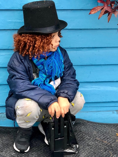 Photo un mignon garçon portant un chapeau et des vêtements chauds en détournant le regard du mur.