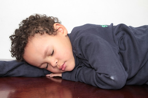 Photo un mignon garçon qui dort sur du bois sur un fond blanc.