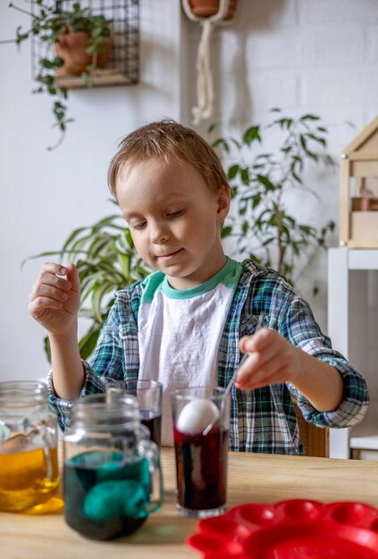 Photo un mignon garçon qui met des œufs dans un pot.