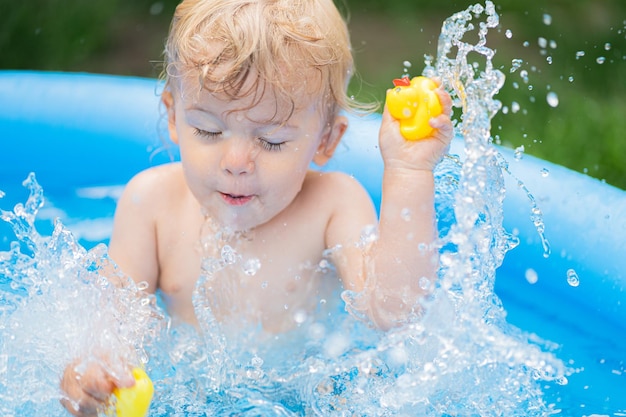 Un mignon garçon qui s'éclabousse dans la piscine.