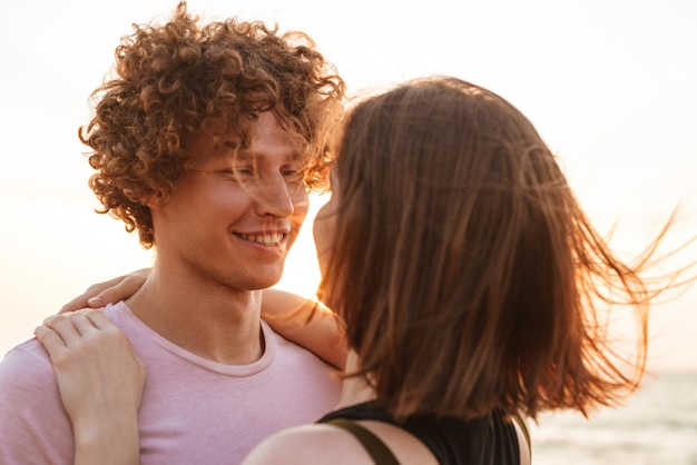 Mignon jeune couple d'amoureux heureux étreignant à l'extérieur sur la plage