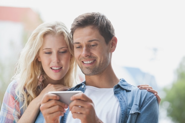 Mignon jeune couple regardant smartphone