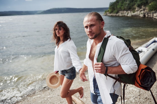 Mignon Jeune Et Couple Sur La Rivière. Un Gars Et Une Femme Avec Des Sacs à Dos Voyagent En Bateau. Concept D'été Voyageur