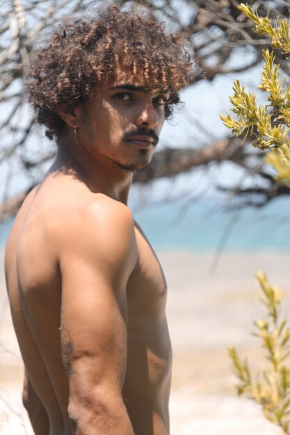 Un mignon jeune homme aux cheveux bouclés sur une île paradisiaque